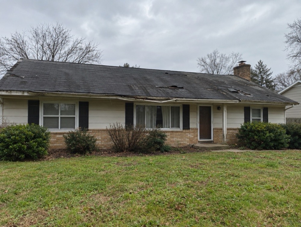 Ranch home with a worn, sagging roof and discolored shingles before replacement
